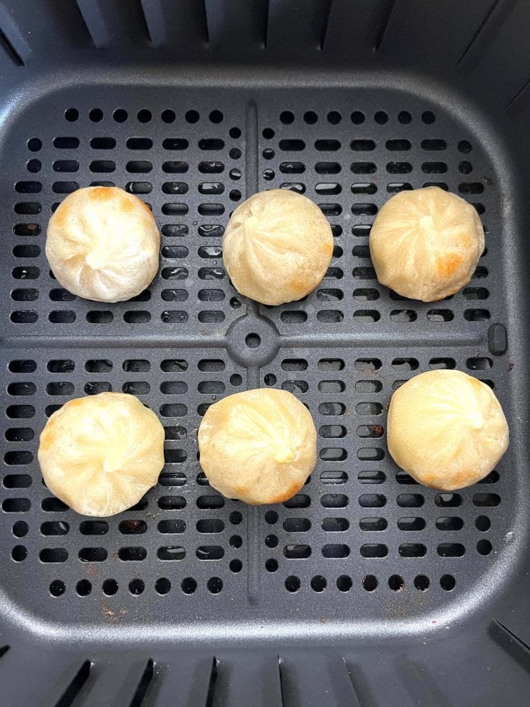 Top view of six perfectly cooked Bibigo dumplings in an air fryer basket, showcasing an easy method for crispy, golden dumplings.