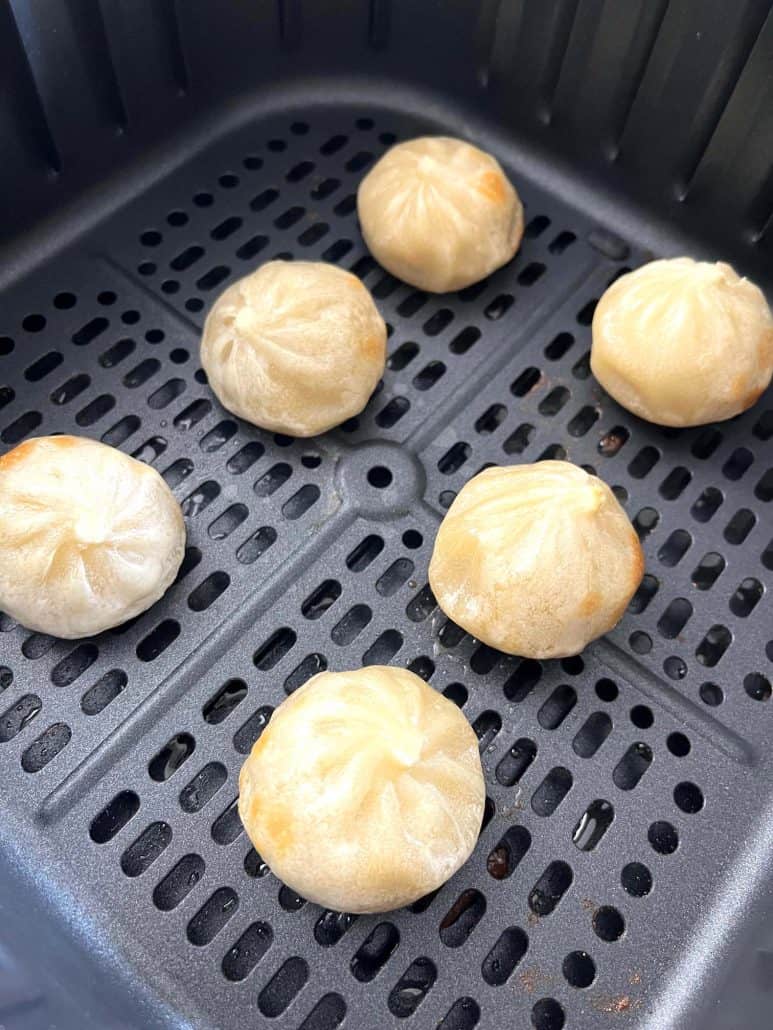 Six Bibigo dumplings cooked in an air fryer, showing a lightly golden, tender texture.