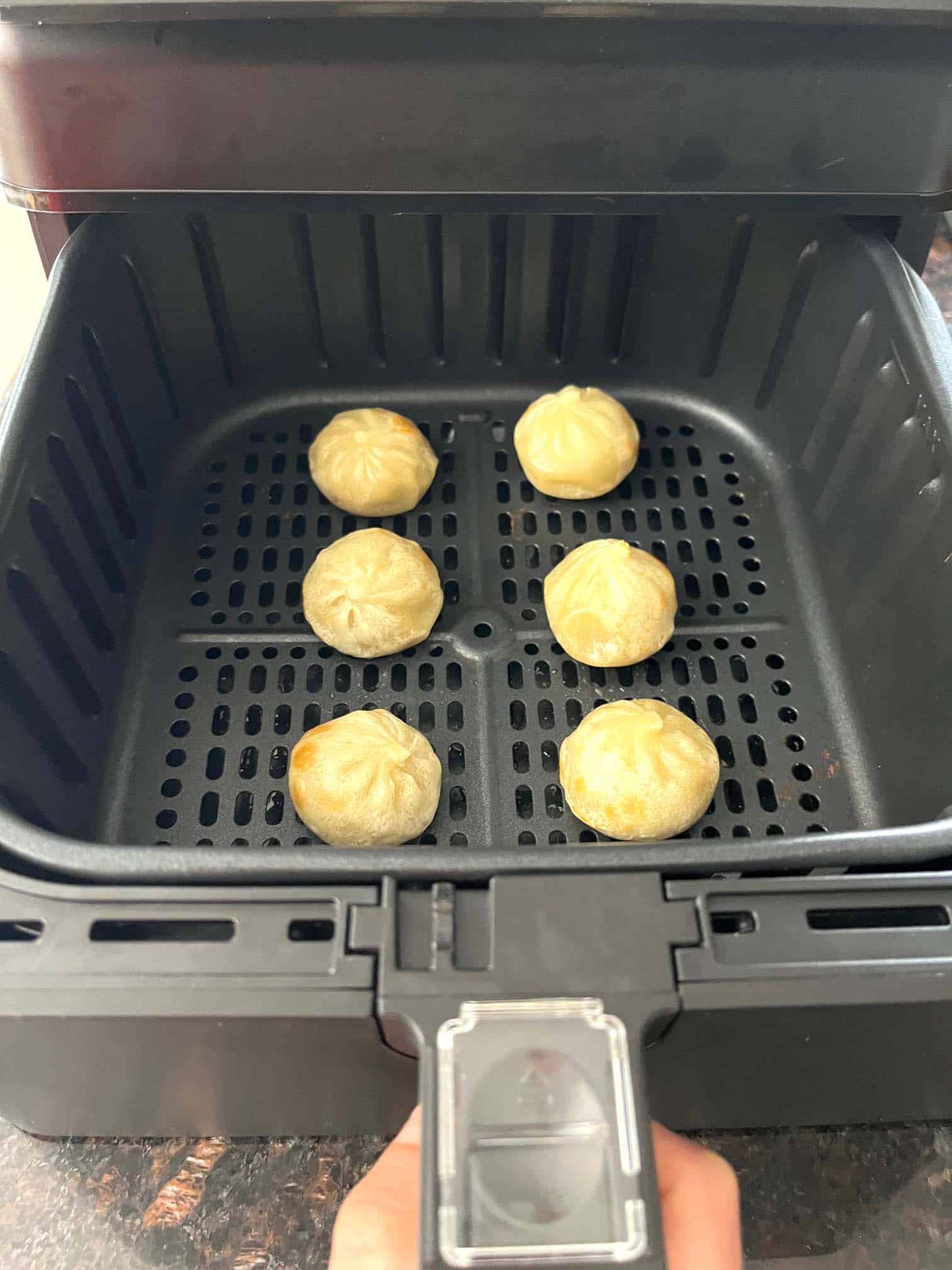 Golden brown dumplings perfectly cooked in an air fryer basket, demonstrating the easy and effective air frying method for frozen Bibigo dumplings.