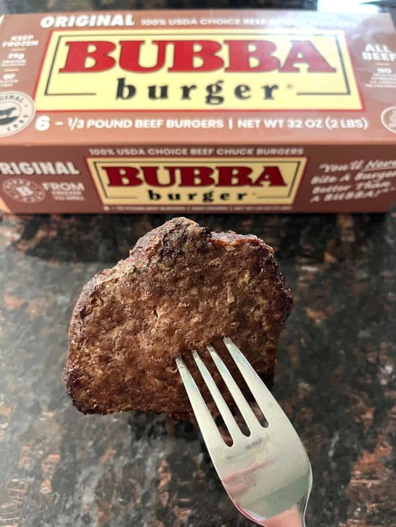 Cooked Bubba Burger held by a fork in front of the Bubba Burger box.