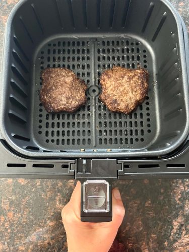 Two frozen Bubba Burgers cooking in an air fryer basket.