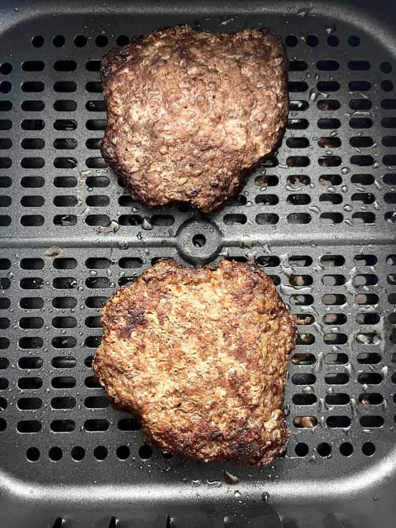 Close-up of two crispy, cooked Bubba Burgers in an air fryer basket.