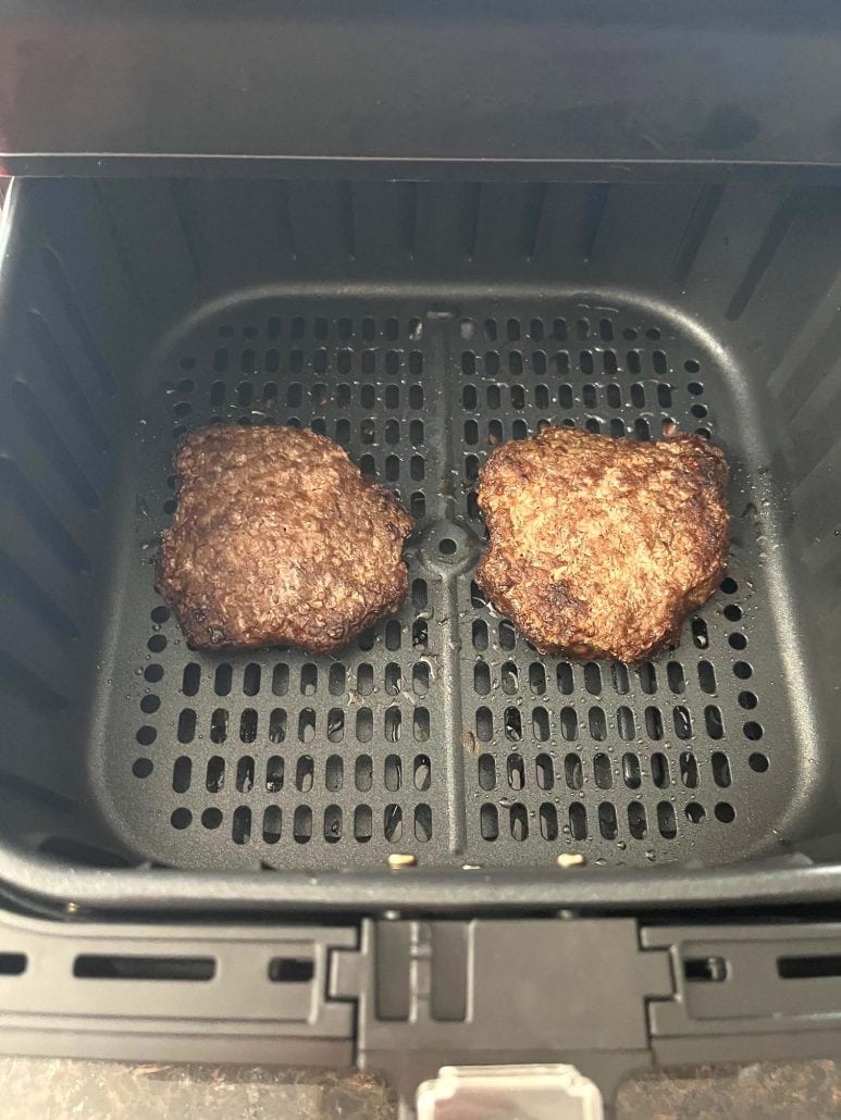 Two fully cooked Bubba Burgers, inside an air fryer basket.