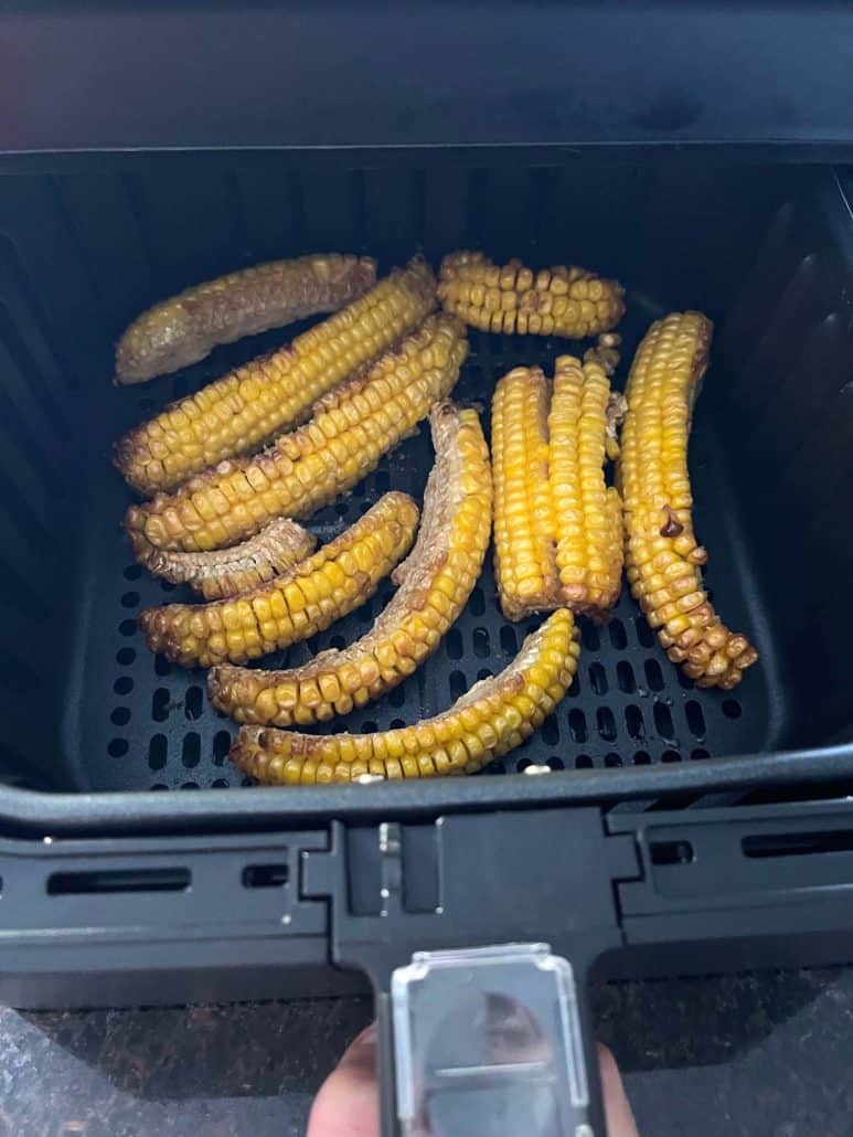 Air fryer basket filled with perfectly cooked seasoned corn ribs.