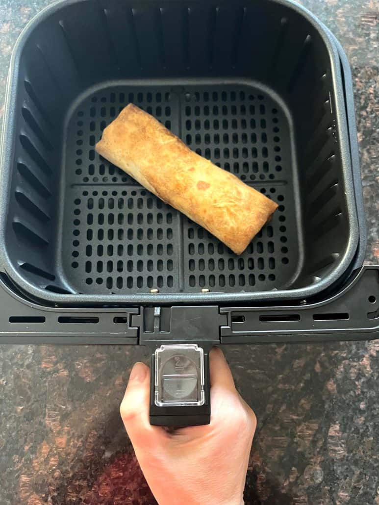 Frozen Kati roll cooking in an air fryer basket, showcasing an easy, no-prep method for achieving a crispy, golden-brown Indian snack.