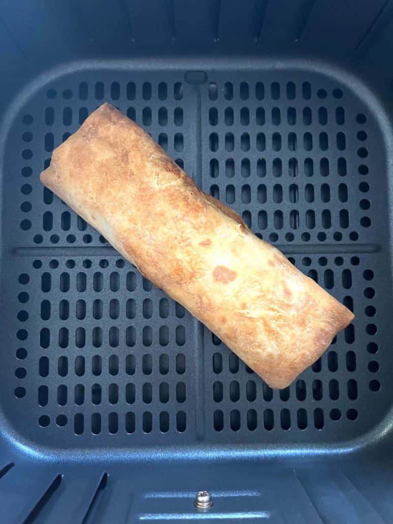 Close-up of a crispy, golden-brown Kati roll in the air fryer basket.