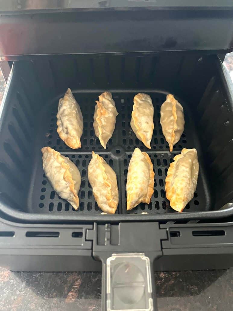 Freshly cooked Crispy golden Mandu dumplings, arranged in an air fryer basket.