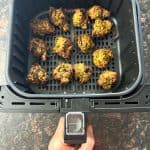 Air fryer basket filled with golden, crispy frozen pakoras after cooking.