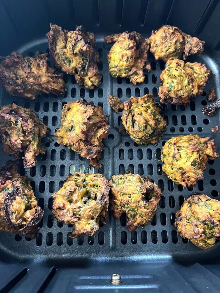 Close-up of crispy, golden pakoras in the air fryer basket.