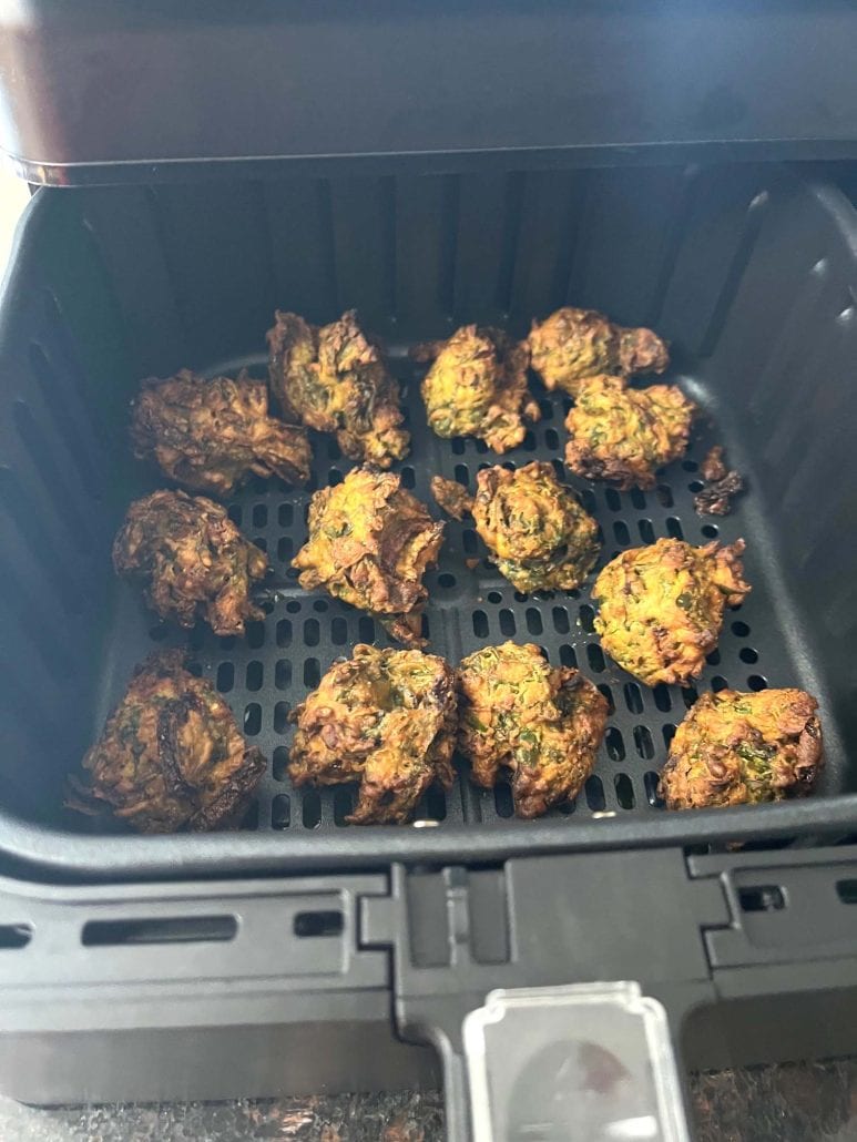 Air fryer basket filled with perfectly cooked golden and crispy pakoras.