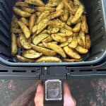 Golden and crispy air-fried potato wedges in an air fryer basket, ready to serve as a delicious and easy side dish.