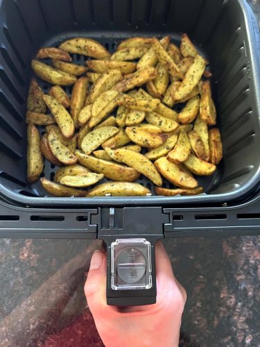 Golden and crispy air-fried potato wedges in an air fryer basket, ready to serve as a delicious and easy side dish.