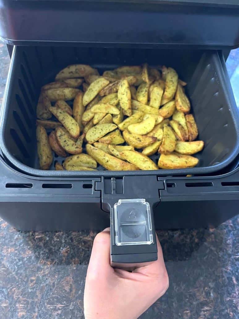 Freshly air-fried potato wedges in an air fryer basket.