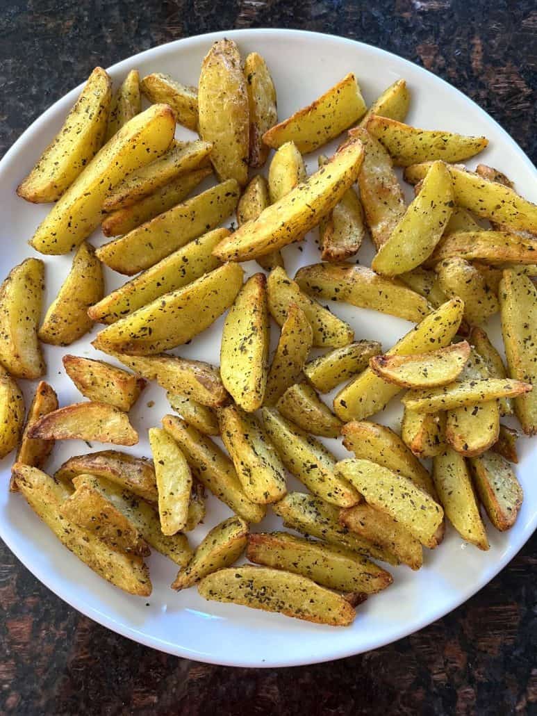 Crispy air-fried potato wedges served on a white plate.