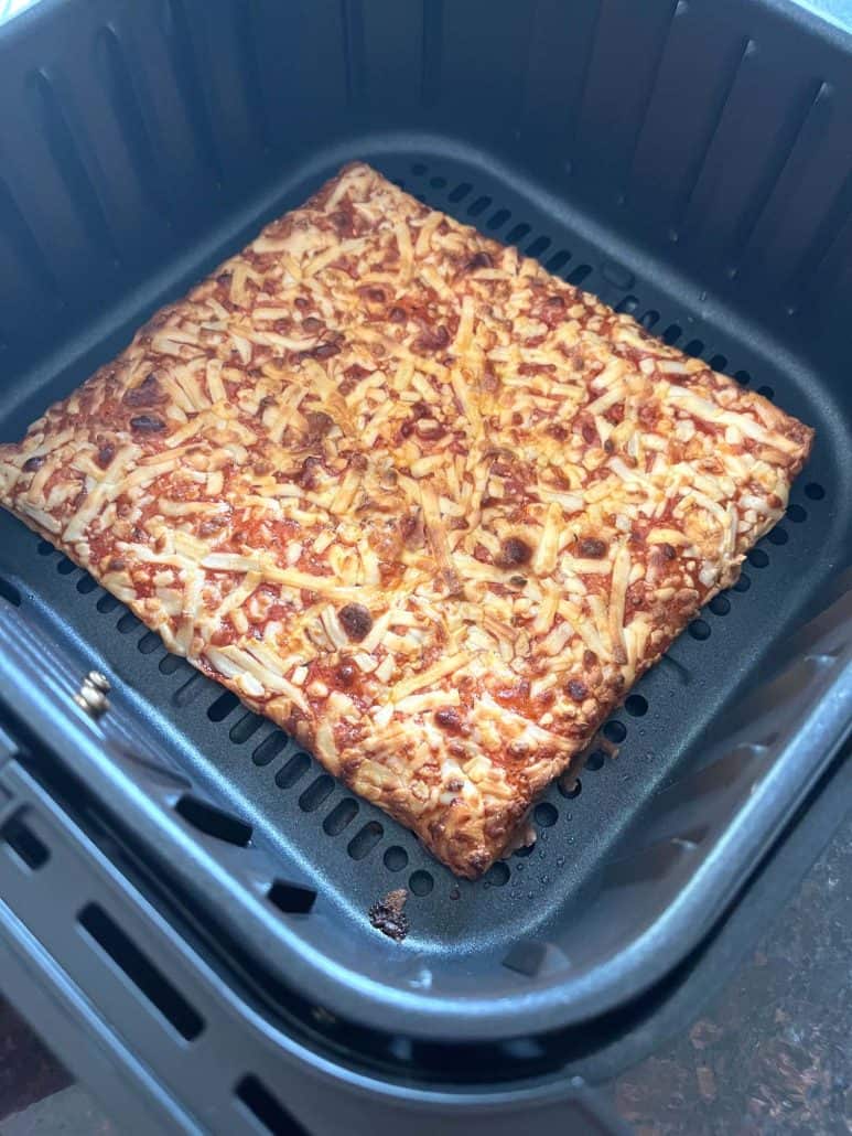 Totino's Party Pizza fully cooked in the air fryer basket with a crispy, golden-brown crust and melted cheese.