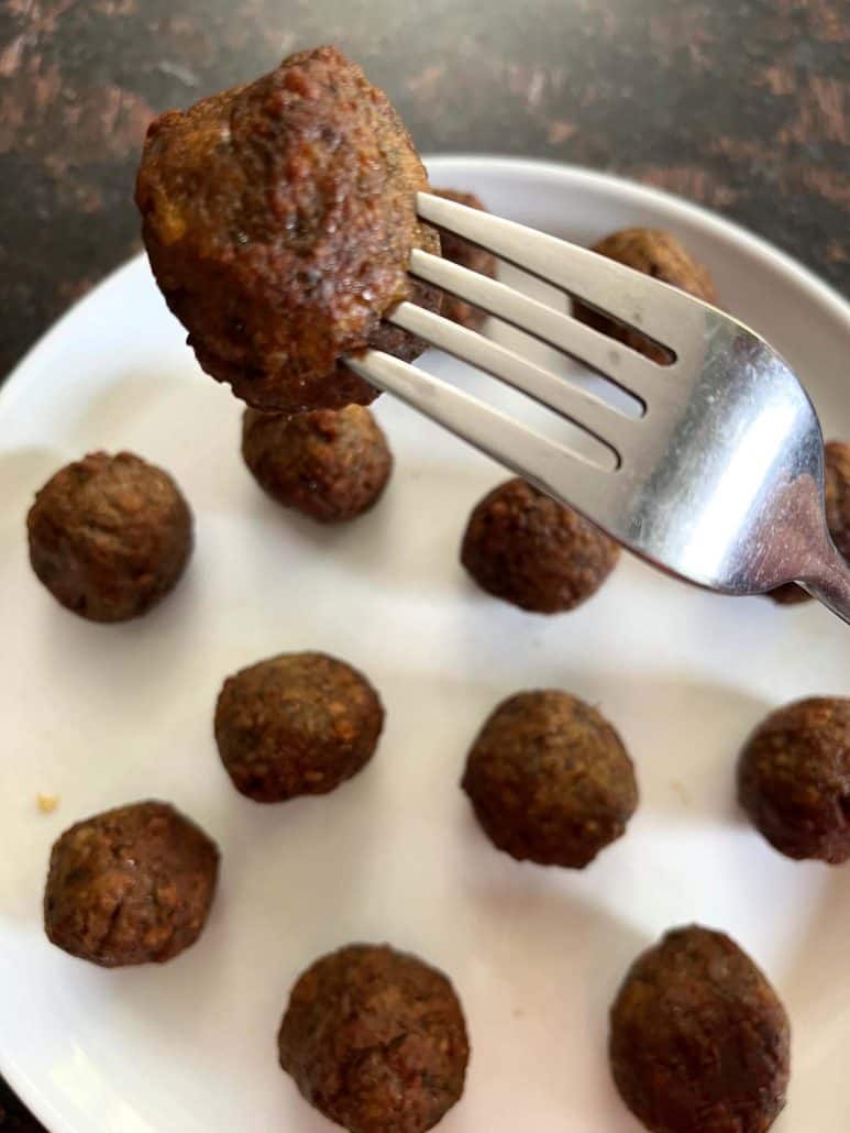 Impossible Meatball above a plate, highlighting the texture and plant-based appeal.