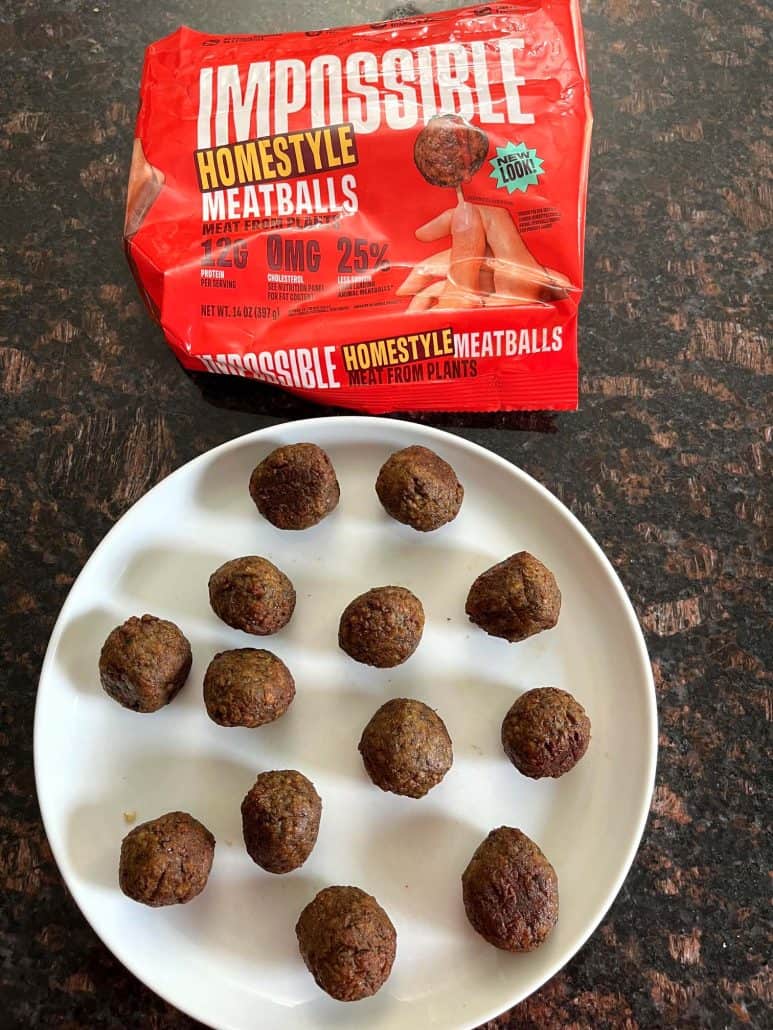 Crispy air-fried Impossible Meatballs served on a plate with the packaging in the background.