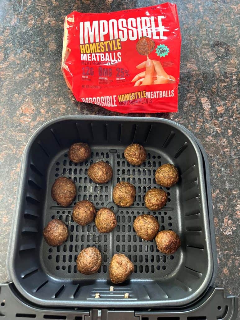 Impossible Homestyle Meatballs in an air fryer basket with the packaging nearby, showcasing an easy vegan cooking option.