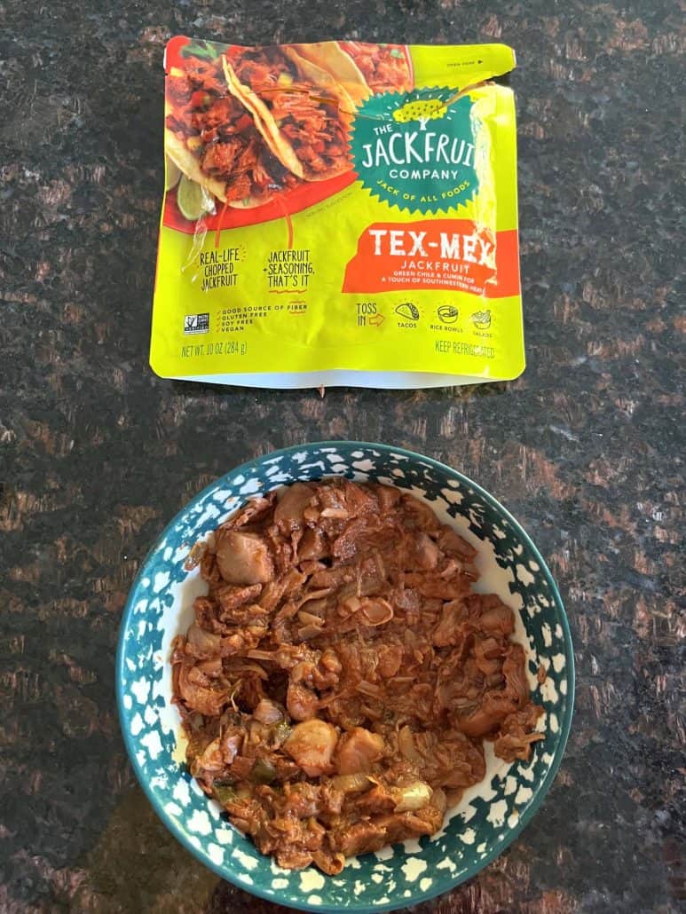 Cooked Tex-Mex jackfruit served in a bowl with the package of The Jackfruit Company Tex-Mex Jackfruit displayed above.