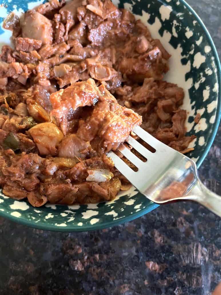 Fork holding a bite of shredded Tex-Mex jackfruit, highlighting the tender texture of the cooked jackfruit.