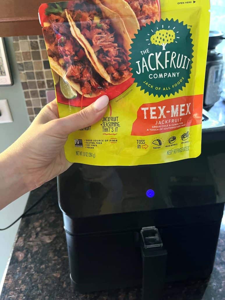 The Jackfruit Company Tex-Mex Jackfruit in front of an air fryer, preparing to make the Air Fryer Jackfruit recipe.