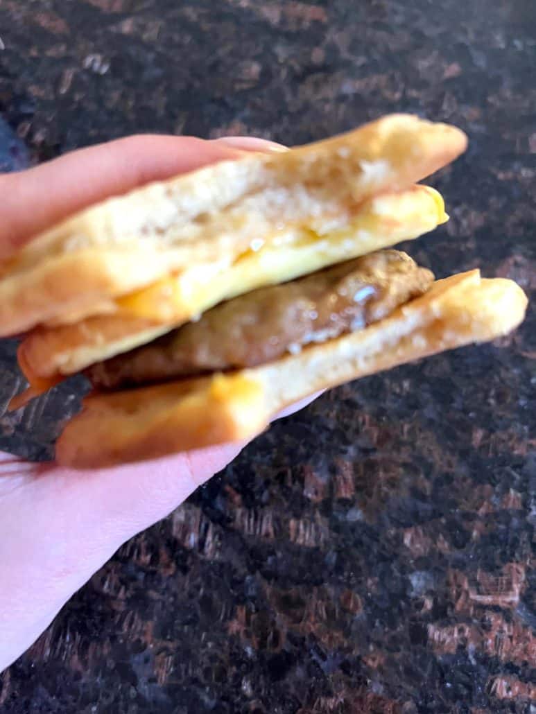 Close-up of a bite taken, showing the layers of sausage, egg, and melted cheese.