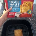 A hand holding a package of Jimmy Dean Toaster Pop Ups alongside perfectly cooked, crispy toaster pop ups fresh from the air fryer, ready to enjoy.