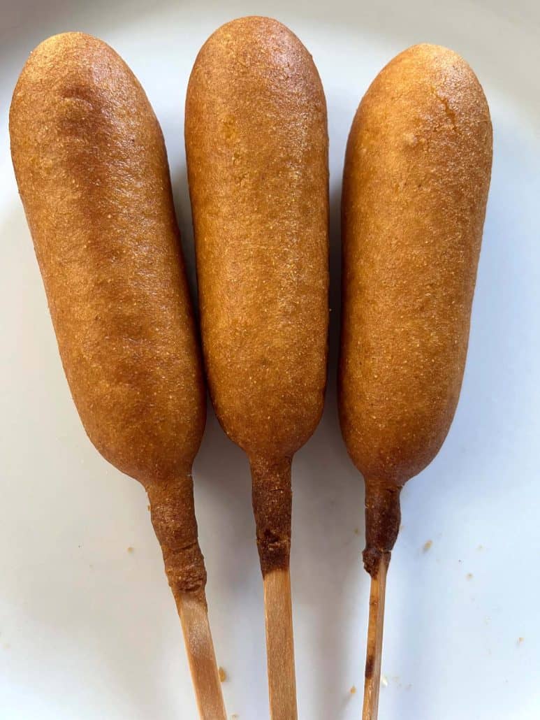 Three cooked vegan corn dogs on a plate.