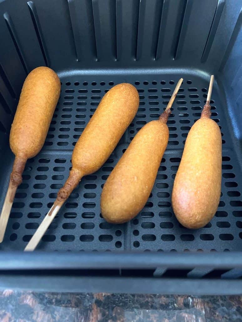 After cooking image of vegan corn dog in the air fryer basket.