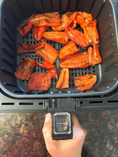 Roasted ancient red sweet peppers in the air fryer basket, perfectly charred and ready to serve as a flavorful side dish.