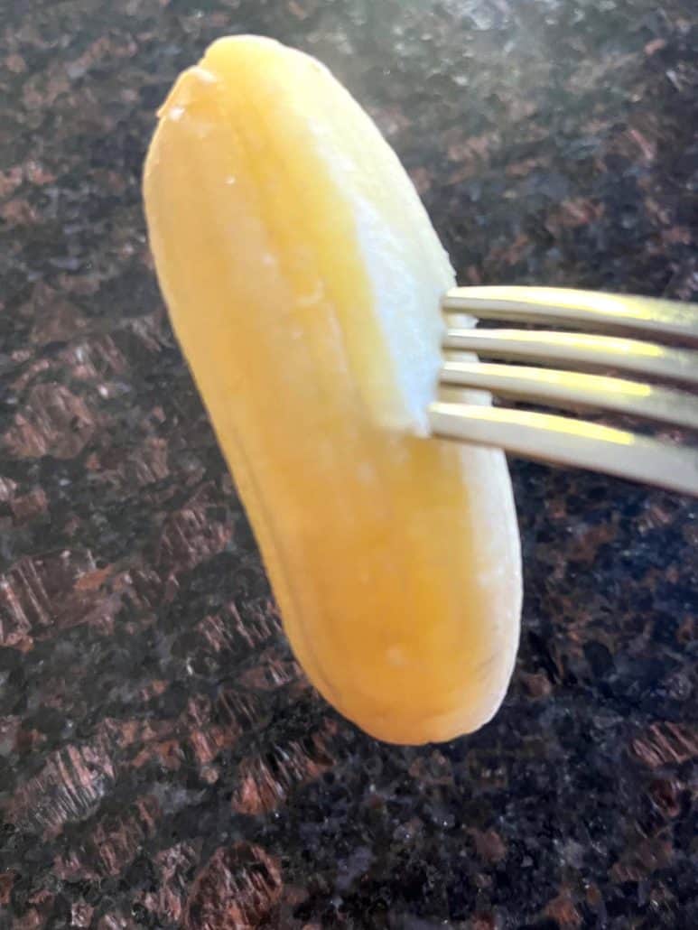 Saba banana held by a fork, ready to be eaten.