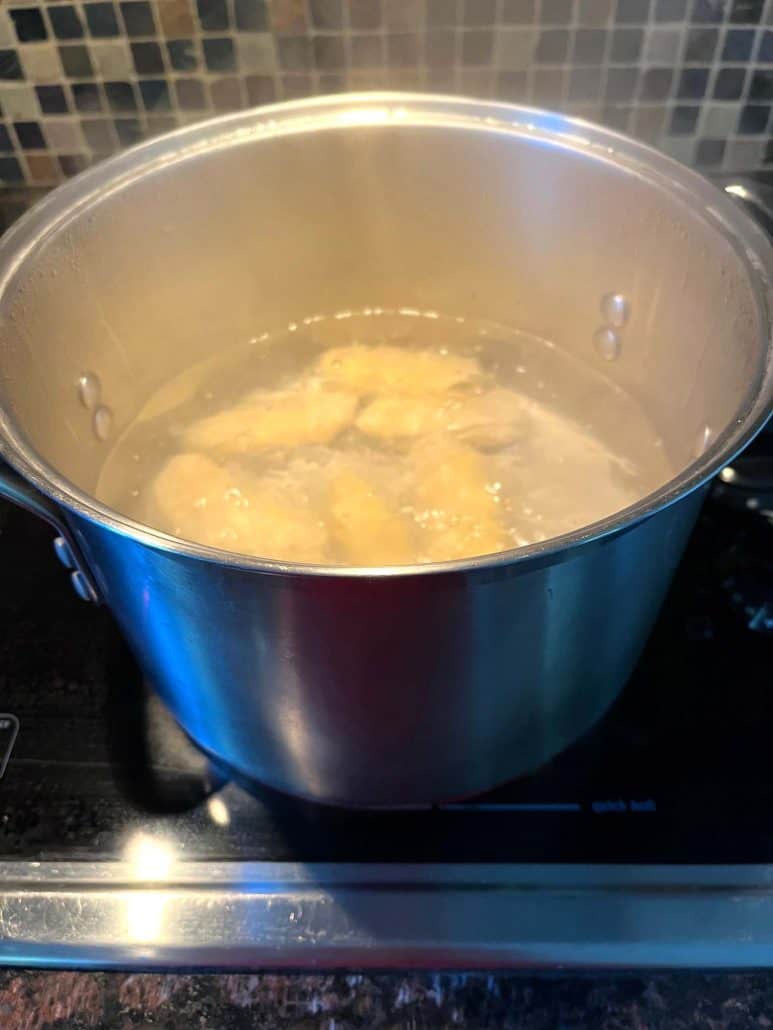 Saba bananas simmering in a boiling pot of water, on the stove.