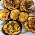 Golden-brown roasted eggplant slices arranged on a white plate