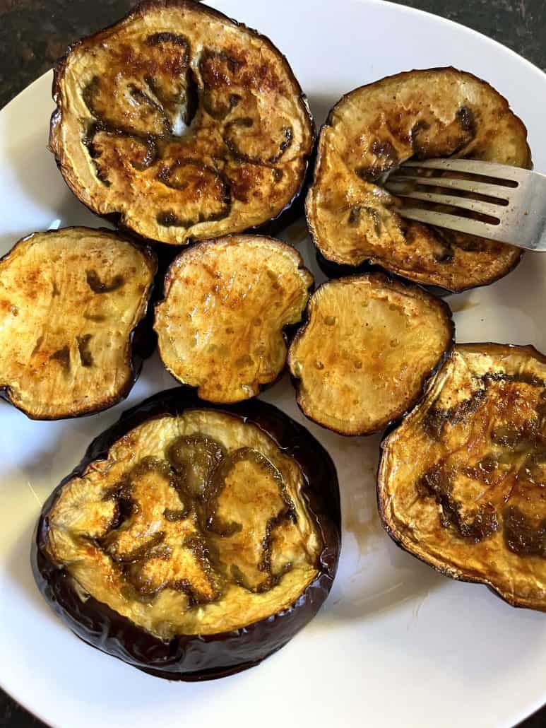 Golden-brown roasted eggplant slices arranged on a white plate