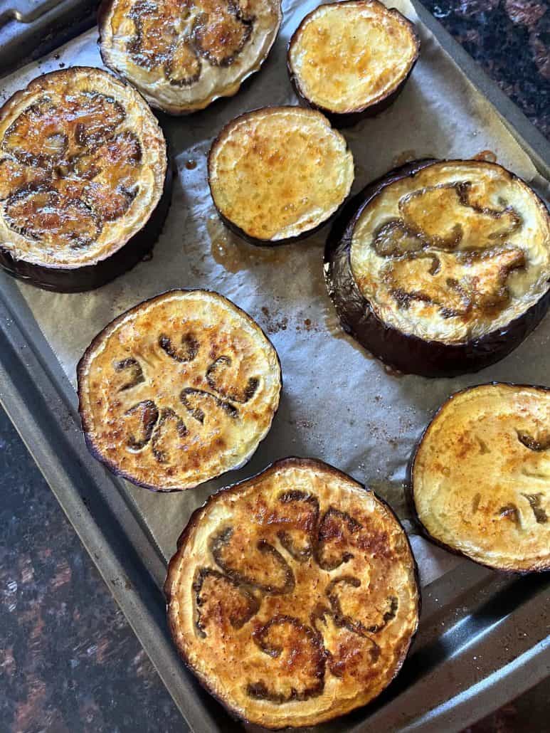 Close-up of roasted eggplant slices on a baking sheet.