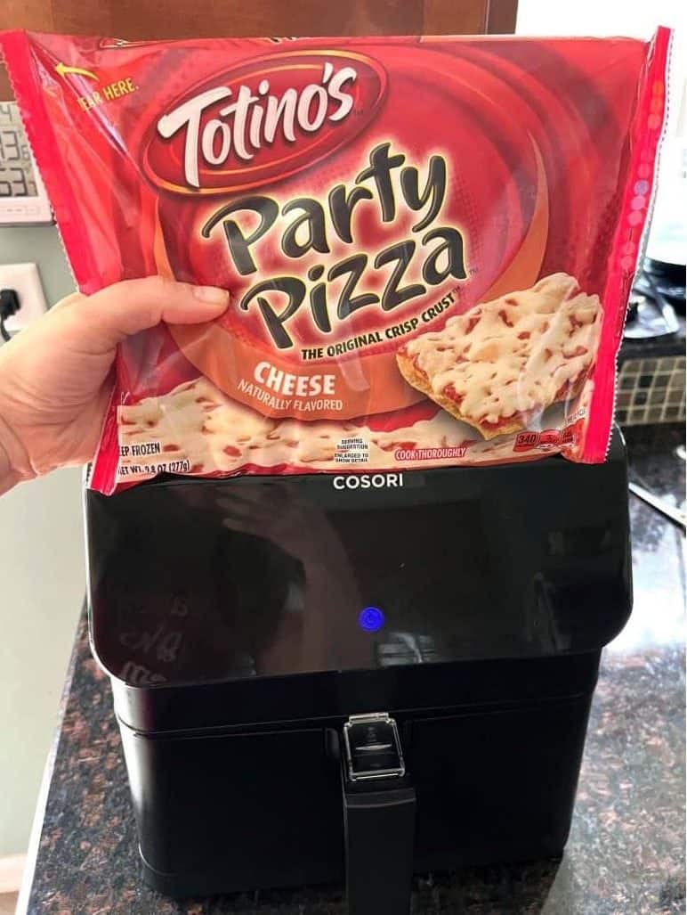 A package of Totino's Party Pizza in front of an air fryer, preparing to cook the pizza.