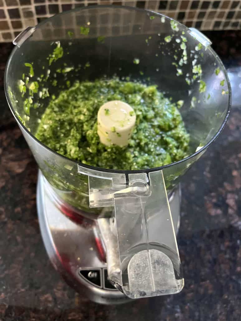 Freshly blended raw tomatillo salsa verde in a food processor.