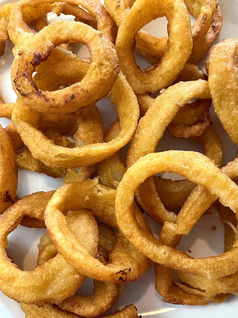 Extreme close-up of crispy, golden onion rings on a plate, showcasing their crunchy, air-fried texture.