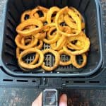 Golden, crispy onion rings cooked in an air fryer basket, showcasing the perfect texture and color achieved with this easy method.