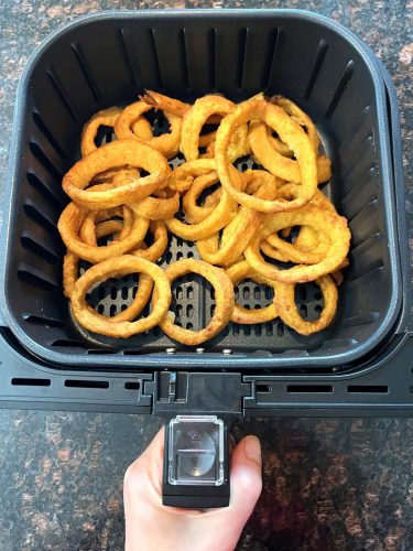 Golden, crispy onion rings cooked in an air fryer basket, showcasing the perfect texture and color achieved with this easy method.