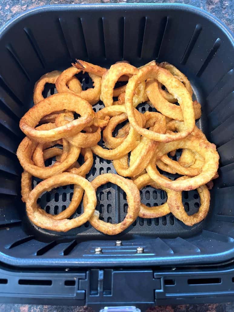 Golden, crispy onion rings in an air fryer basket, showcasing their perfectly cooked texture.