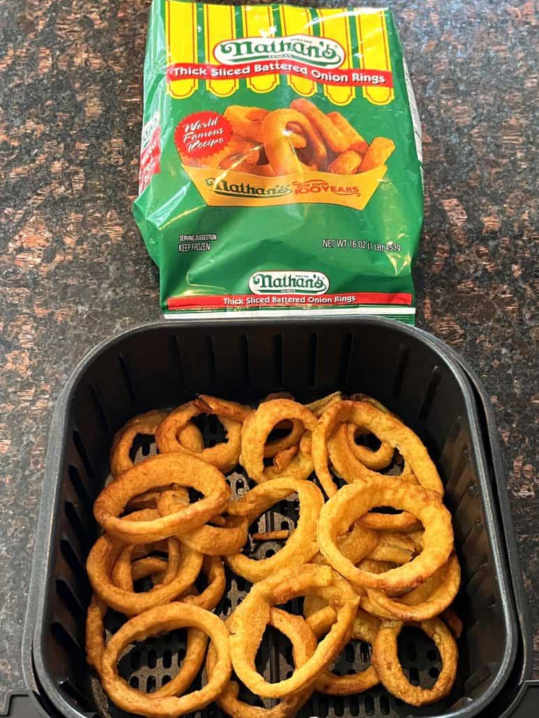 Air fryer basket filled with crispy onion rings, displayed alongside the Nathan’s Thick Sliced Battered Onion Rings package.