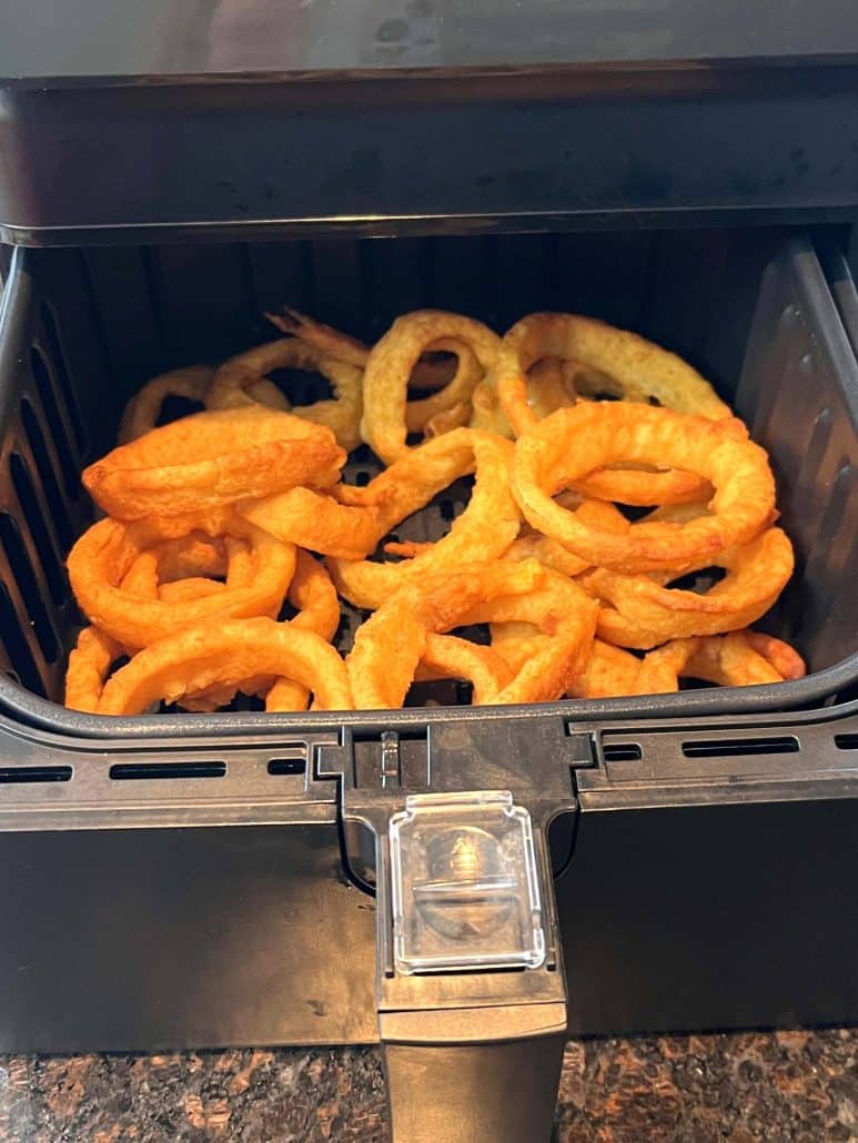 Freshly cooked, golden brown onion rings straight from the air fryer basket.