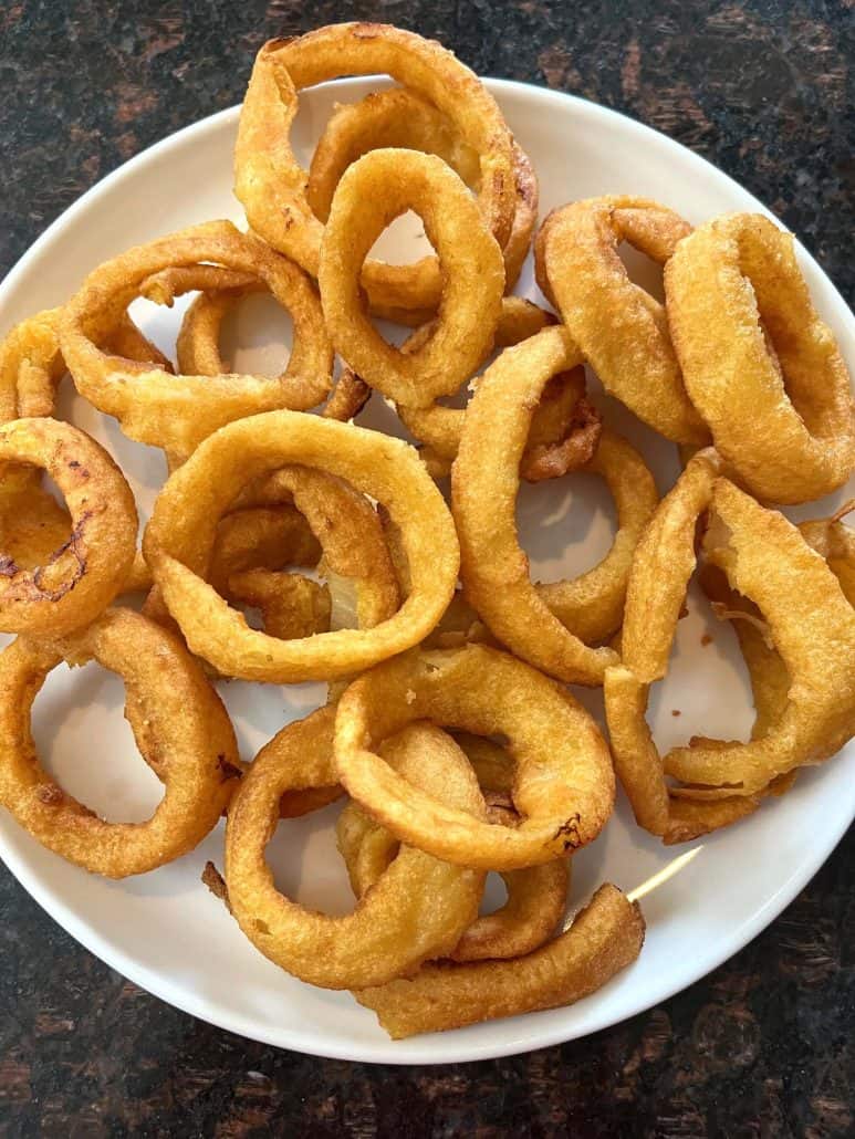 A plate of crispy, golden onion rings, freshly cooked and ready to serve.