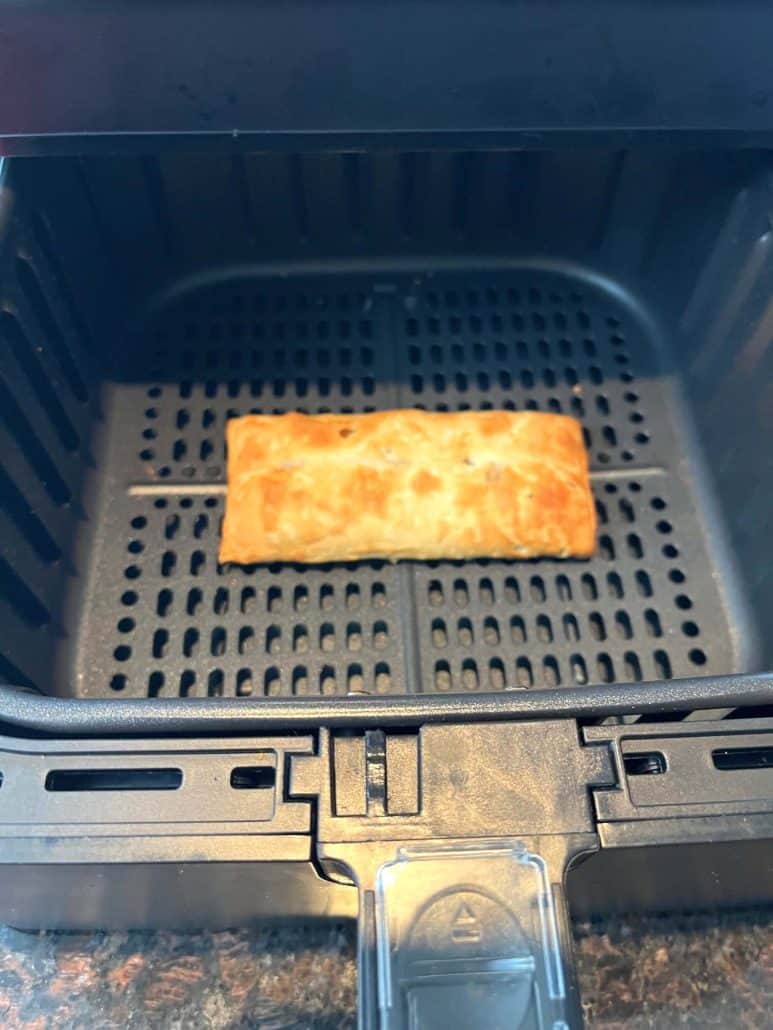 Close-up of a perfectly golden pizza stick inside an air fryer basket.