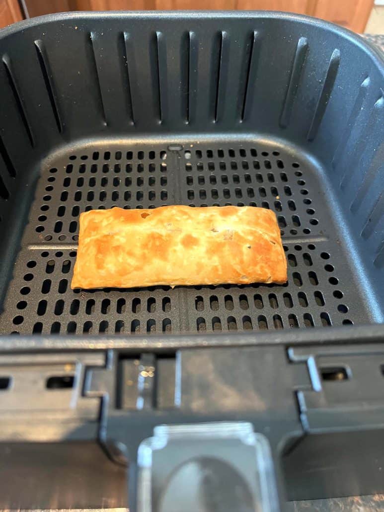 Crispy pizza stick sitting in an air fryer basket, perfectly cooked