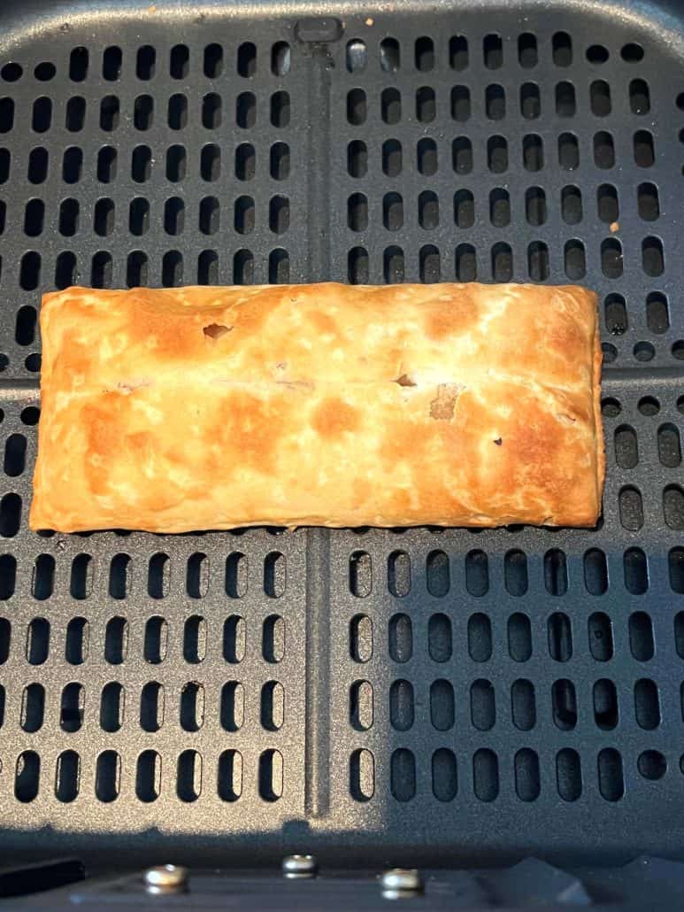 Perfectly golden pizza stick on an air fryer basket, highlighting its crispy texture.