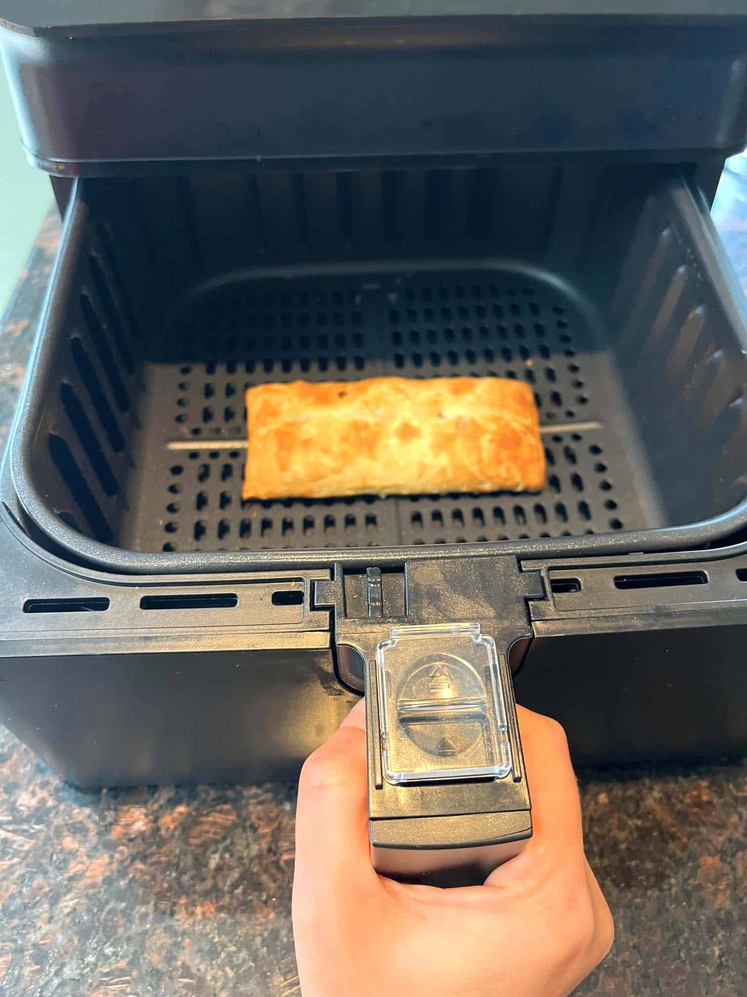 Golden-brown pizza stick freshly cooked in an air fryer basket, showcasing the crispy perfection achieved through air frying.