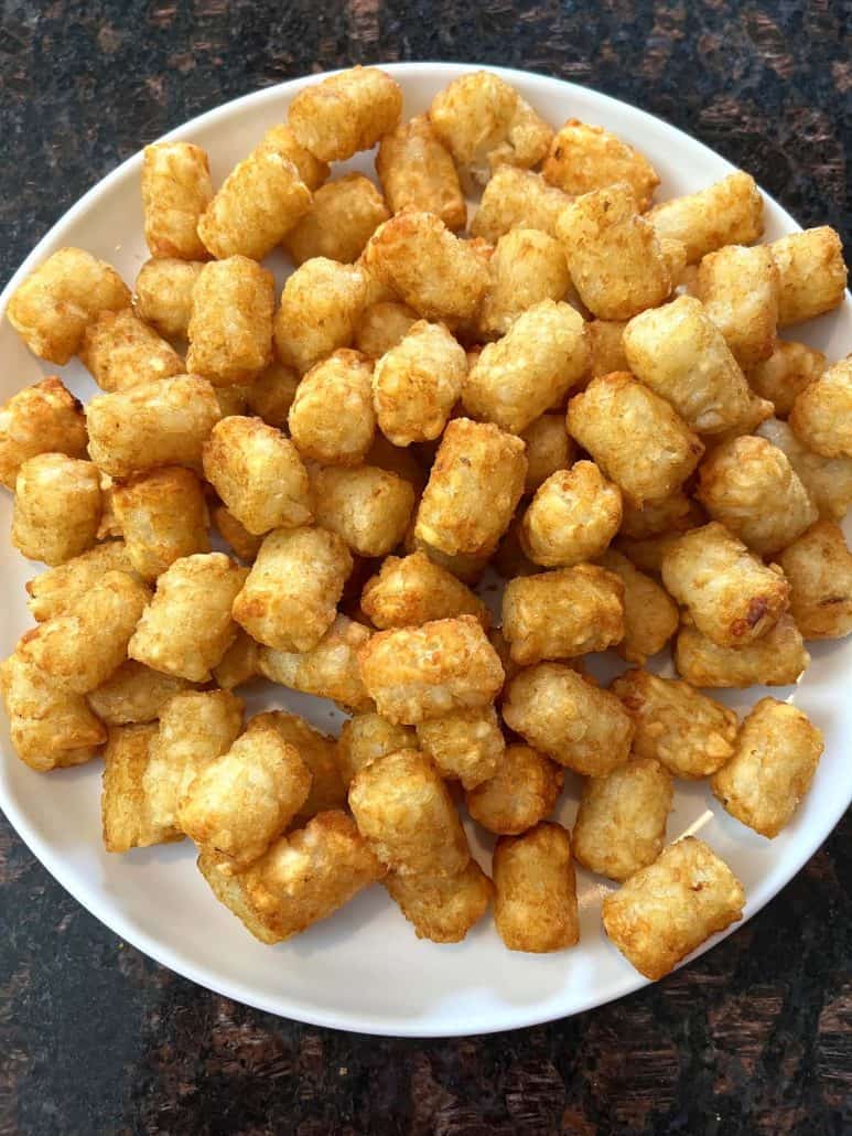 Plate full of golden, crispy Sonic tater tots, freshly cooked and ready to serve.