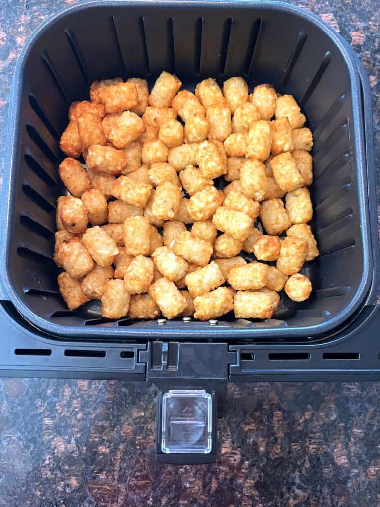 Freshly cooked Sonic tater tots in the air fryer basket, golden brown and perfectly crispy.